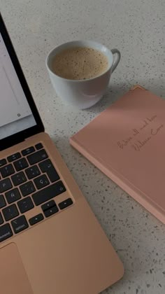 an open laptop computer sitting next to a cup of coffee