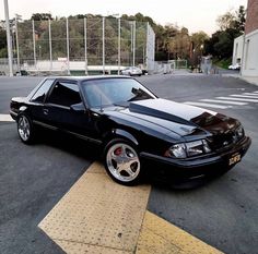 a black car parked on the side of a road next to a parking space with no cars