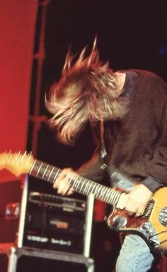 a man with long hair playing an electric guitar