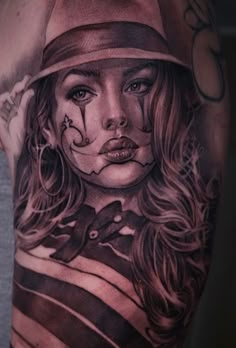 a woman's arm with tattoos on it, including a girl wearing a hat