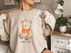 Women's Cute Teddy Bear Halloween Sweatshirt - Cozy Fall Fashion, women's Halloween sweatshirt, cute fall sweatshirt, teddy bear Halloween top, trick or treat sweater, autumn fashion, cozy fall clothing, women's fall sweatshirt. Get ready for the spooky season with our adorable Women's Cute Teddy Bear Halloween Sweatshirt! This light beige sweatshirt features a charming teddy bear holding a tiny orange pumpkin, complete with a playful "trick or treat" slogan. Perfect for adding a touch of whimsy Cute Fall Loungewear Sweatshirt, Fall Bear Print Crew Neck Top, Bear Print Crew Neck Top For Fall, Beige Sweatshirt, Bear Halloween, Halloween Top, Sweater Autumn, Fall Clothing, Sweatshirt Cute