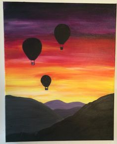 two hot air balloons flying in the sky at sunset with mountains and hills behind them