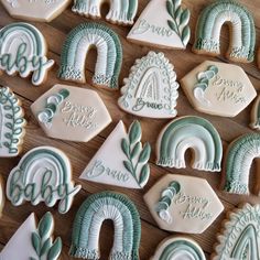 decorated cookies with green and white frosting are arranged on a wooden surface, including the letters