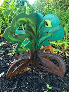 a wooden sculpture with green leaves on it in the grass near some bushes and trees