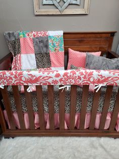 a baby crib with pink, grey and white bedding on top of it