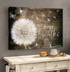 a white table with a wooden sign that says just breathe and a dandelion on it