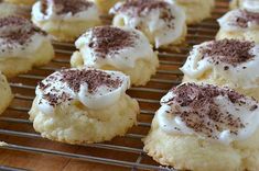 cookies with white frosting and chocolate sprinkles on a cooling rack