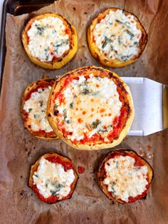 mini pizzas with cheese and spinach are on a baking sheet next to a spatula