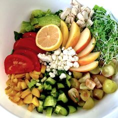 a white bowl filled with lots of different types of fruit and vegtables