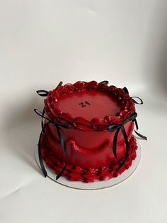 a three layer red cake with black ribbon around the edges on a white tablecloth