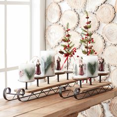 a wooden table topped with candles and christmas decorations next to a wall covered in wood slices