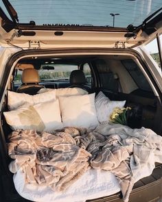 the back end of a car with blankets and pillows in it's trunk area