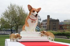 a dog statue on top of a cake with three puppies standing next to it