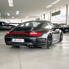 a black porsche parked in a parking garage