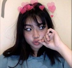 a girl with hearts on her head making a funny face while holding her finger to her lips