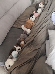 there are many stuffed animals lined up on the bed sheets and pillows, along with other stuff animals