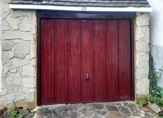 a red garage door is open in front of a stone building