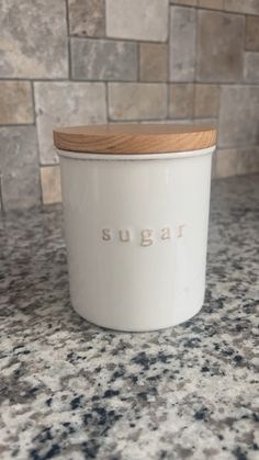 a white sugar jar sitting on top of a counter next to a tile backsplash