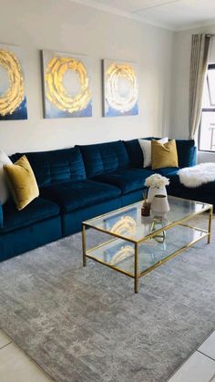 a living room with blue couches and two paintings on the wall