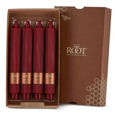 four beeswax candles in a cardboard box next to a brown package with the words root on it