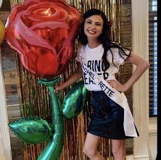 a woman standing next to a giant rose balloon