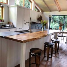 a kitchen island with stools in front of it and an open floor plan to the outside