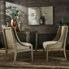 two chairs sitting next to each other in front of a table with vases on it