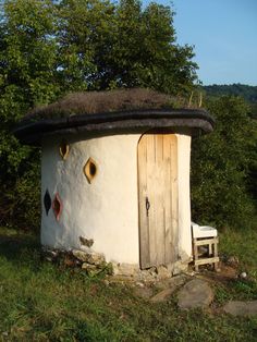 an outhouse in the middle of a field with a door and window on it