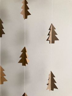 paper christmas trees hanging from strings on a wall