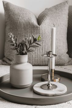 a tray with a candle, vase and plant on it