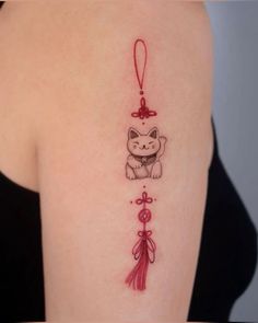 a woman's arm with a tattoo on it that has a cat and tassel hanging from it