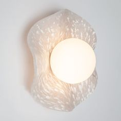 a light that is on the side of a white wall mounted fixture with an egg in it