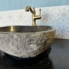 a bathroom sink made out of granite and gold faucet