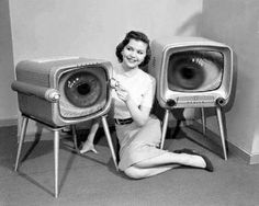 a woman sitting on the floor next to two televisions