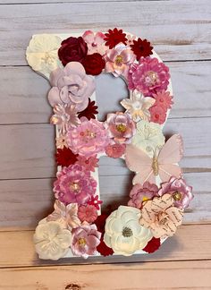 the letter b is made out of flowers and paper machs on a wooden surface