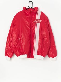 Vintage rare Coca Cola puffer jacket in cherry red. This jacket is official merch from Coca Cola and is a really rare piece to get your hand on!  The jacket has the Coca Cola logo on the left chest with white racing lines and features two front hand pockets with zip closure and a stretchy white hem. Made from a soft, lightweight material.  Our recommended size: Large  Label says: XL  Condition: Very good Material: 100% nylon  Measurements in inches: Pit to pit: 24 Shoulders: 20.5 Front length: 2 Sporty Red Hooded Puffer Jacket, Red Outerwear With Padded Collar For Streetwear, Red Padded Collar Outerwear For Streetwear, Red Puffer Outerwear For Streetwear, Retro Winter Nylon Outerwear, Retro Nylon Winter Outerwear, Retro Red Hooded Outerwear, Red 90s Style Streetwear Outerwear, 90s Red Outerwear For Streetwear