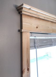 a wooden window frame hanging on the side of a wall next to a window with blinds