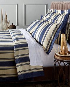 a bed with blue and white striped comforter next to a night stand on a rug