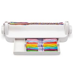 a white sewing machine with several different colored threads in the bottom drawer and on top of it