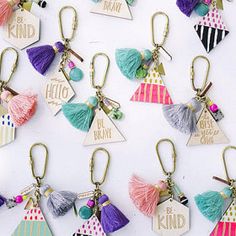 a bunch of key chains with tassels and tags attached to them, all in different colors