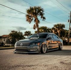 a gray car parked on the street next to palm trees