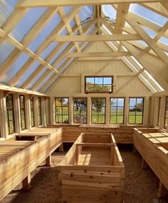 the inside of a building with wooden benches and windows on each side, in front of an open field