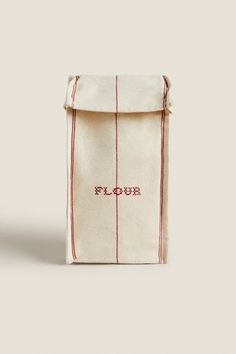 a small bag with the word flour printed on it, sitting in front of a white background