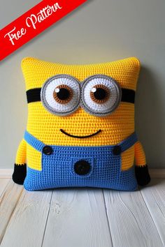 a crocheted minion pillow sitting on top of a wooden floor next to a wall