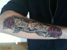 a man with a tattoo on his arm that says, love is here and two roses