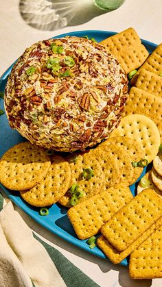 a platter with crackers, cheese and nuts on it next to a bowl of dip