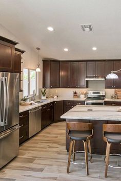 a large kitchen with stainless steel appliances and wooden cabinets, along with two bar stools