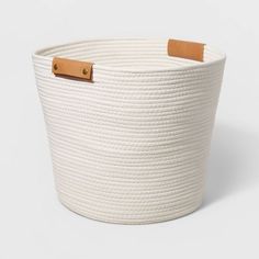 a white rope basket with leather handles