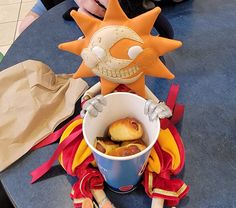 a stuffed animal sitting on top of a bucket filled with food next to other items