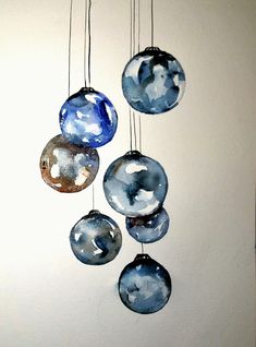 three glass ornaments hanging from strings on a wall